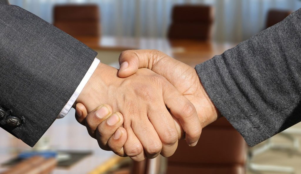 Image d'une poignée de main entre 2 personnes en costumes
